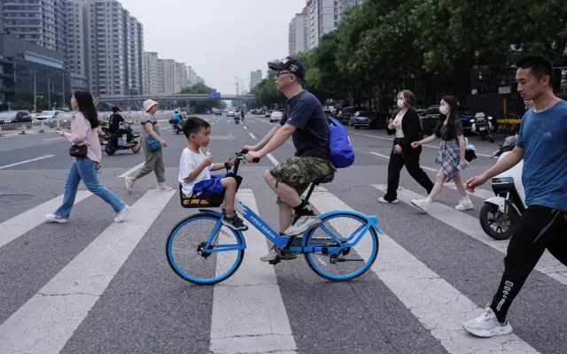 A person rides a bicycle with a child sitting in the basket in Beijing, China July 14, 2024